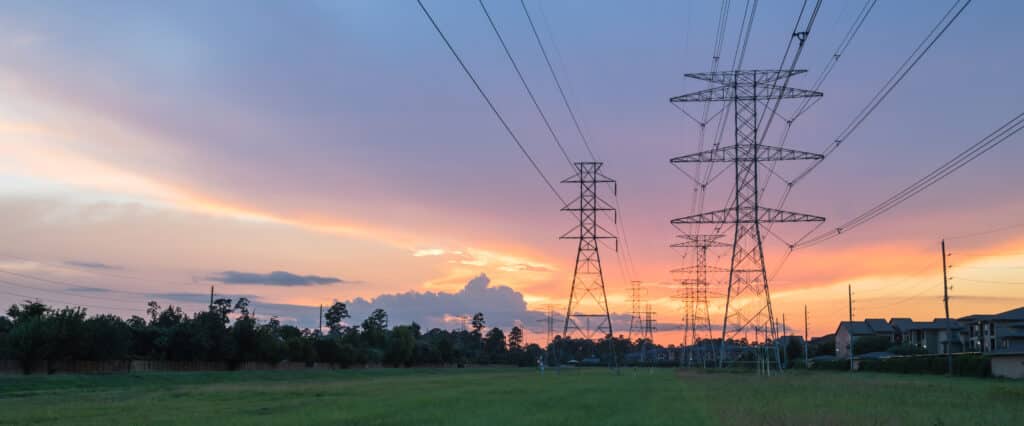 Group silhouette of transmission towers (power tower, electricity pylon, steel lattice tower) at twilight in US