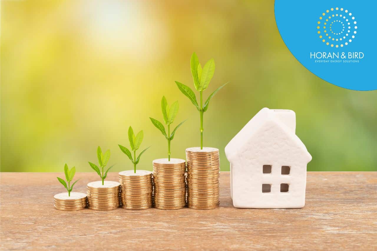 Model house and coin stack with tree on blur green background