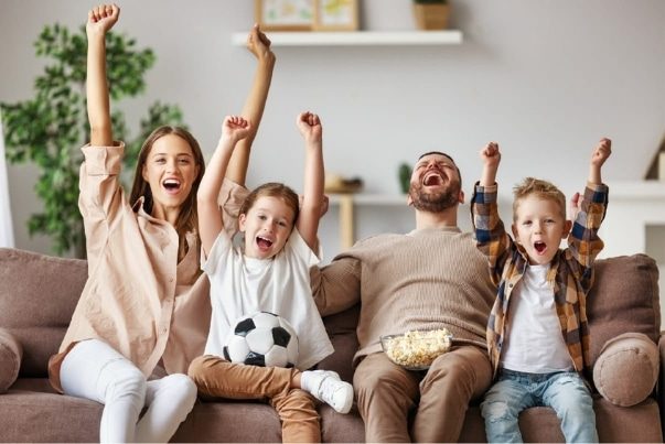 Family image with four members on the couch jumping up in excitement